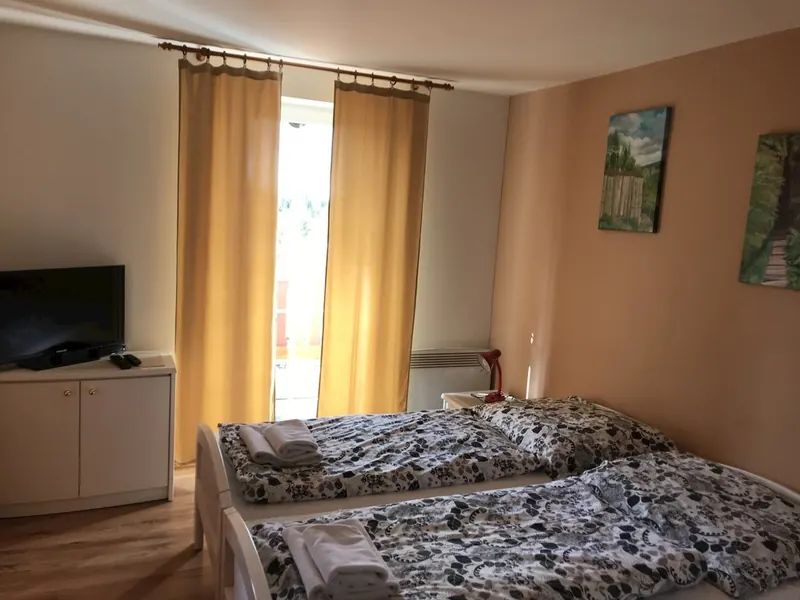 Ložnice se dvěma lůžky, televizí a balkonovými dveřmi
